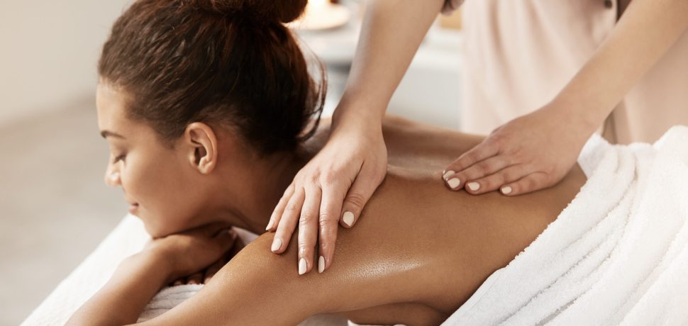 Attractive african girl having massage relaxing in spa salon. Closed eyes.